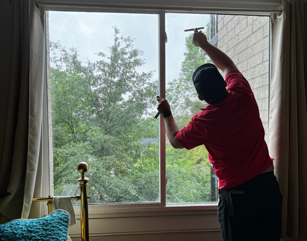 Sun Shade & Graphics window technician applying window tinting to a residential bedroom window.